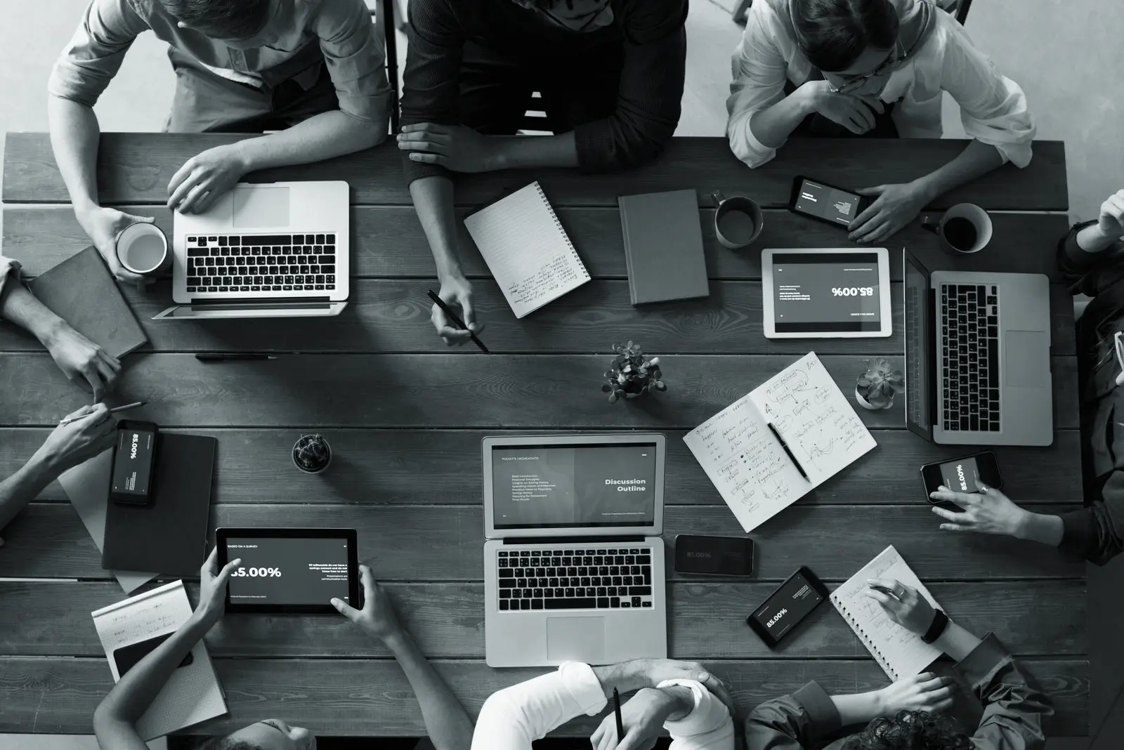 A team working together around a table covered in laptops, notes and dashboards